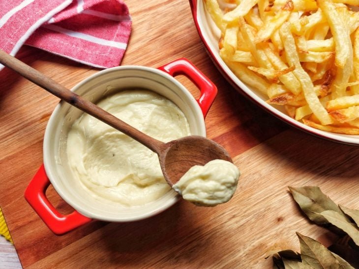 Recipiente com molho holandês acompanhado de batatas fritas em outro recipiente ao lado.