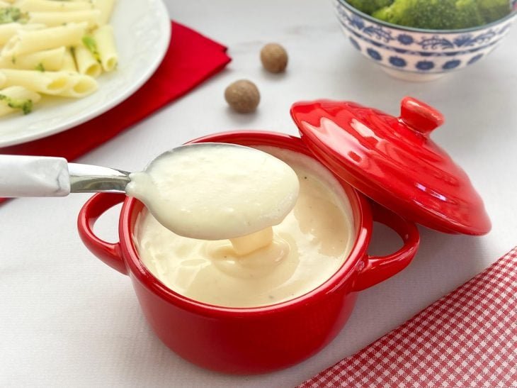 Panela pequena vermelha com molho bechamel.